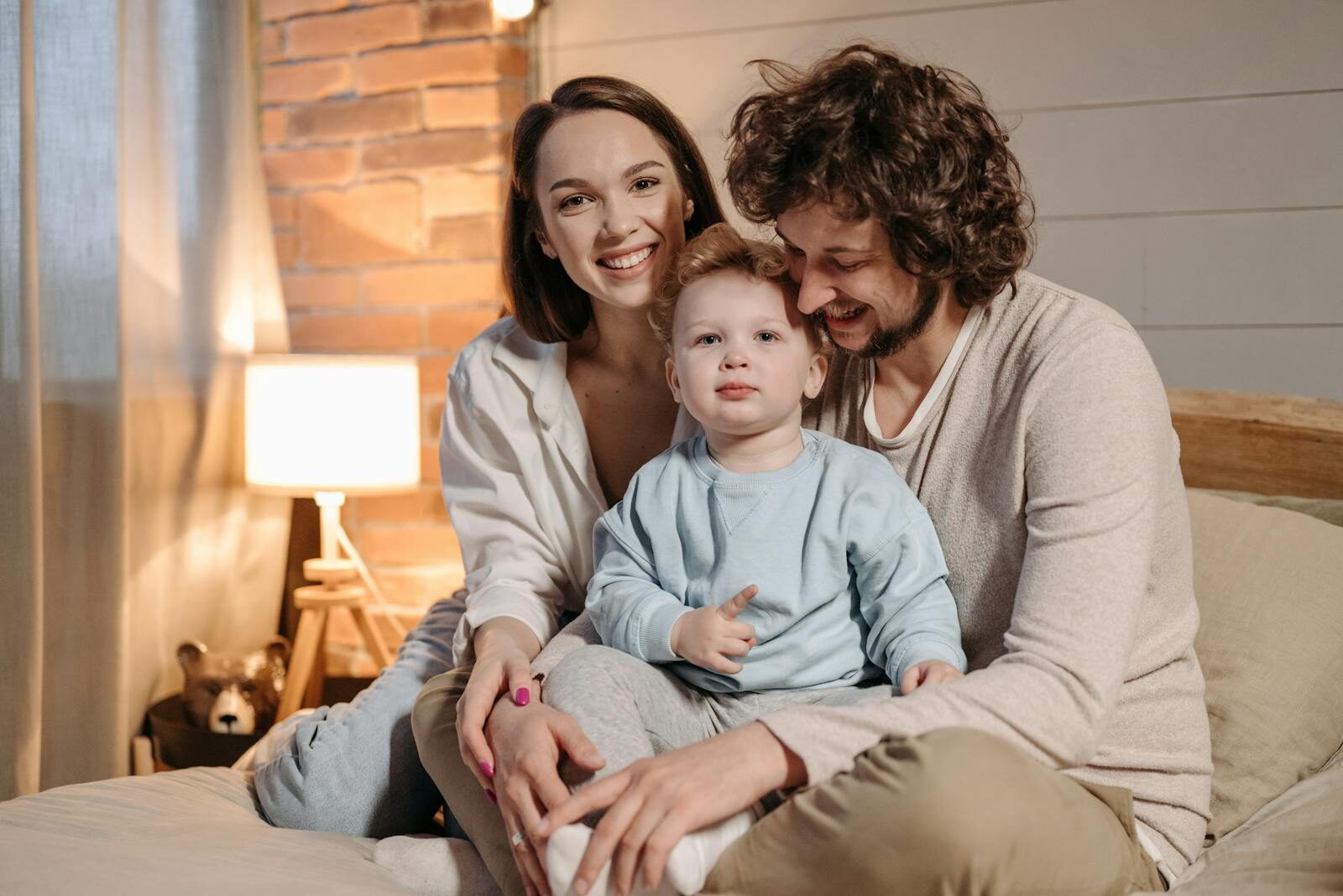 A joyful family moment captured indoors with parents and child bonding on a bed.